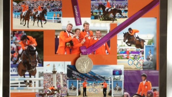 De medaille en diverse foto's, in een lijst.